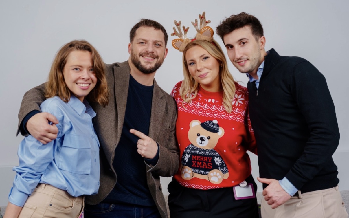 Colleagues at a Christmas gathering, one wearing a festive red jumper
